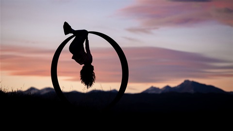 a young person swings from a large ring sculpture