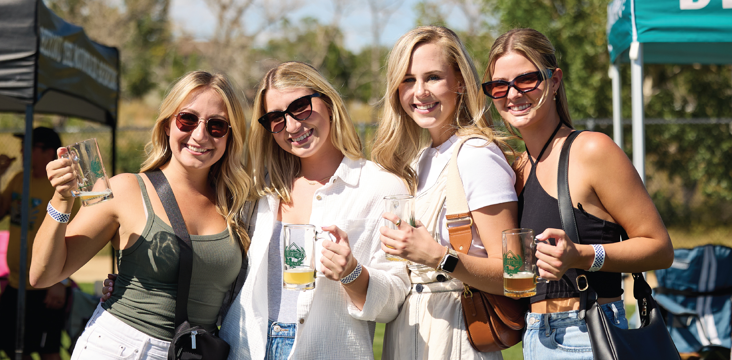 Group of friends smiling while showing their Beer Fest mugs.
