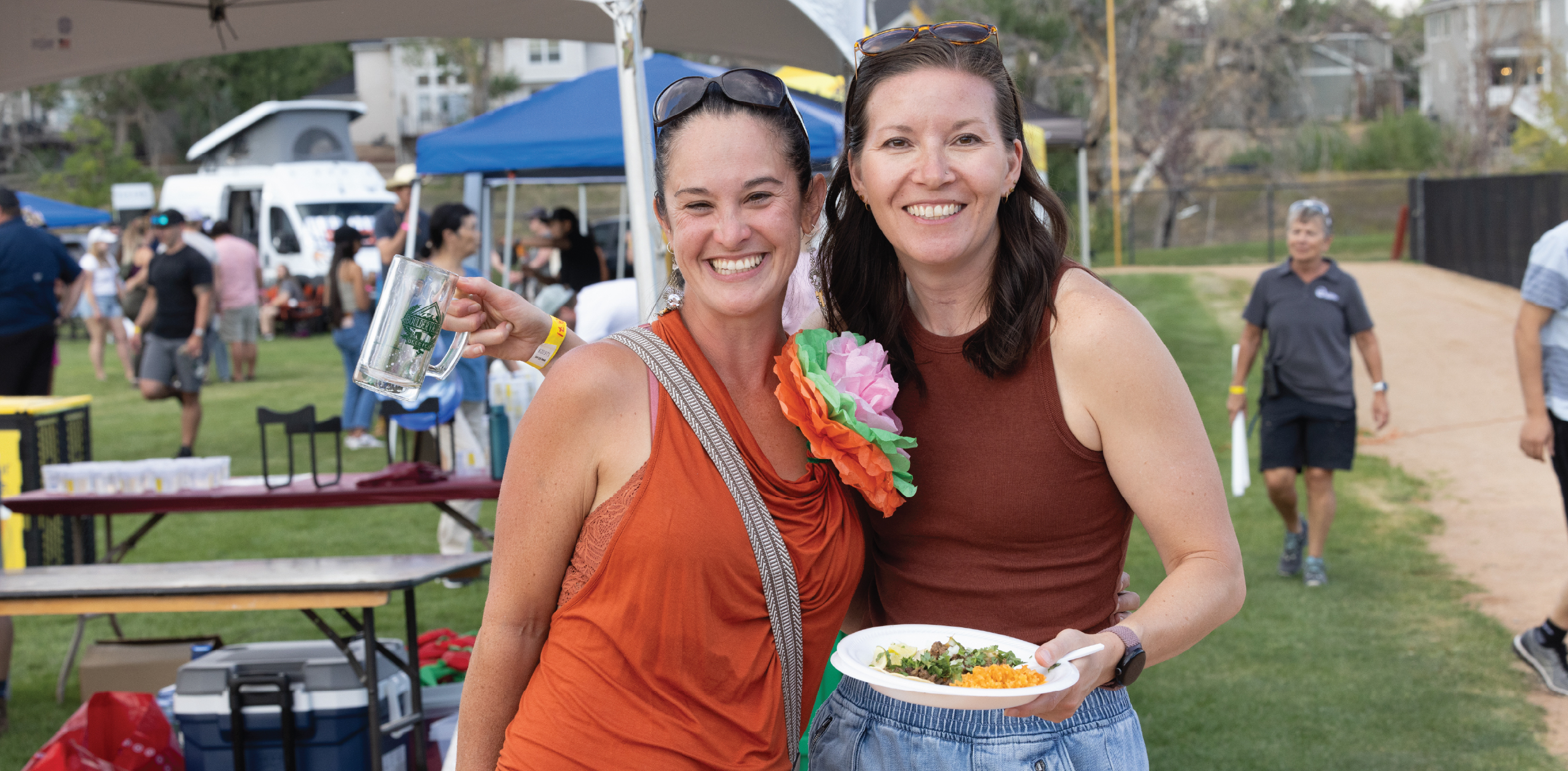 Two friends smiling while holding plates of tacos.