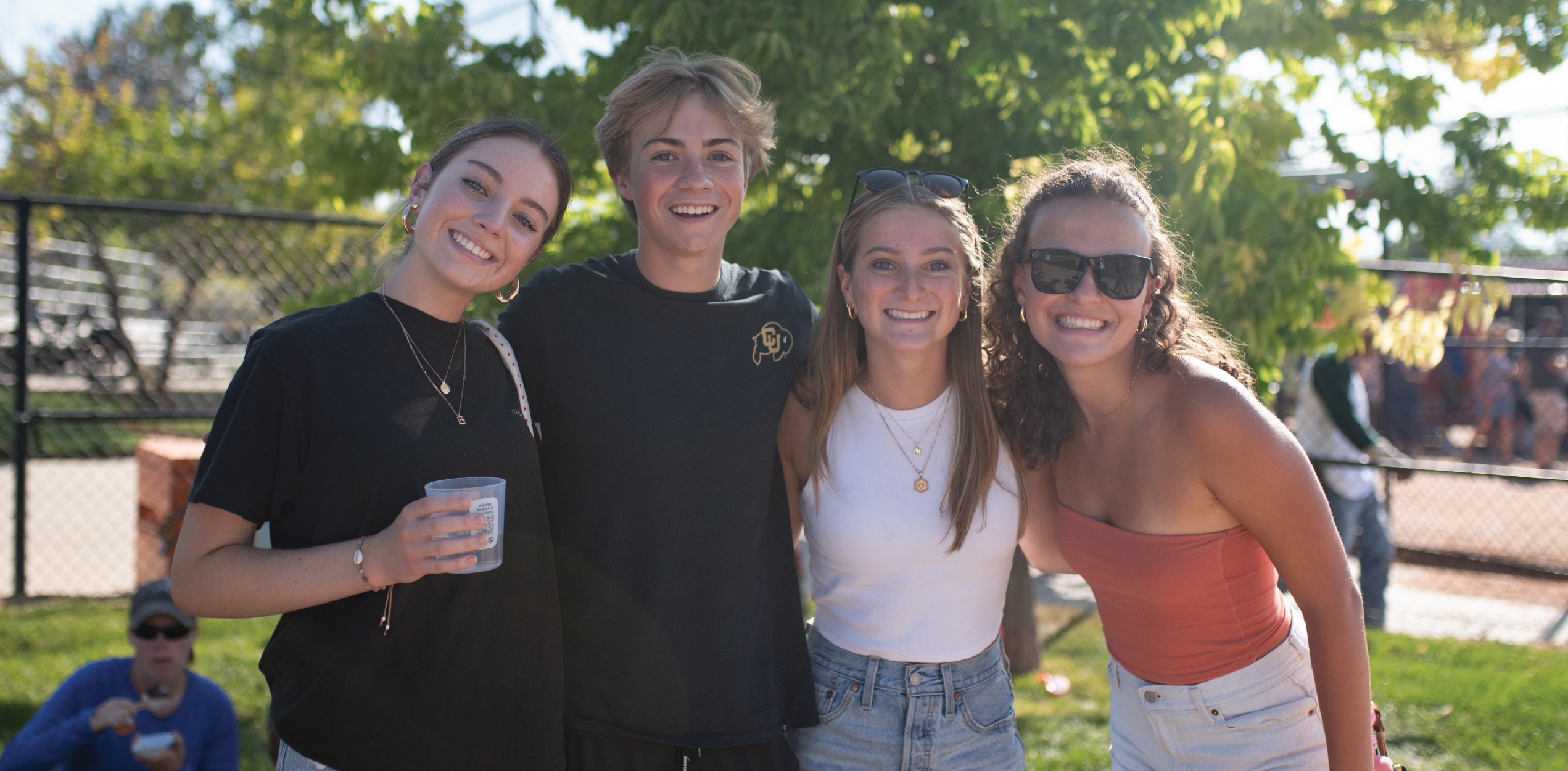 Group of young adults smiling while holding chili fest cups.