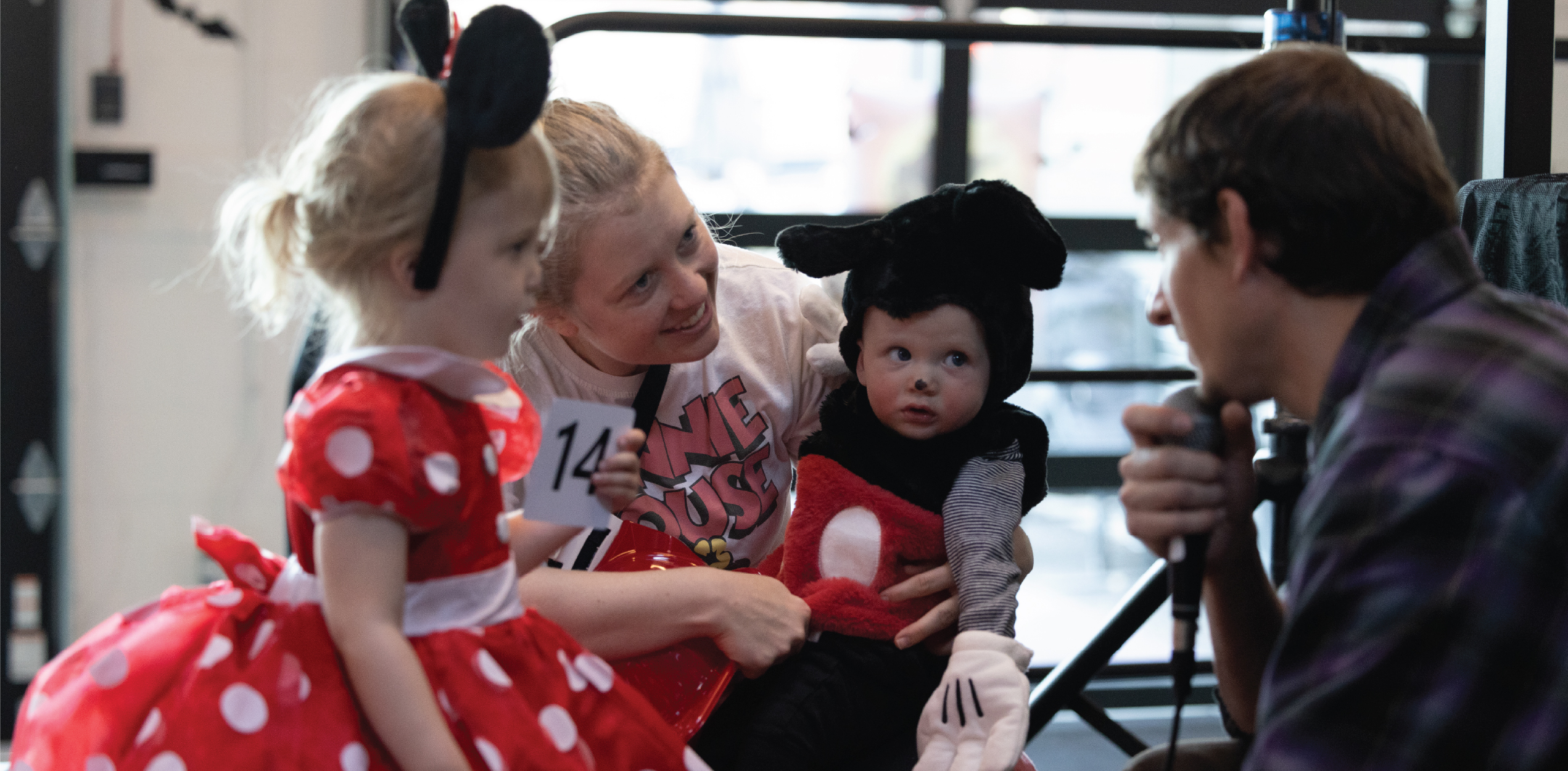 Parent holding children while telling the MC what their costumes are.