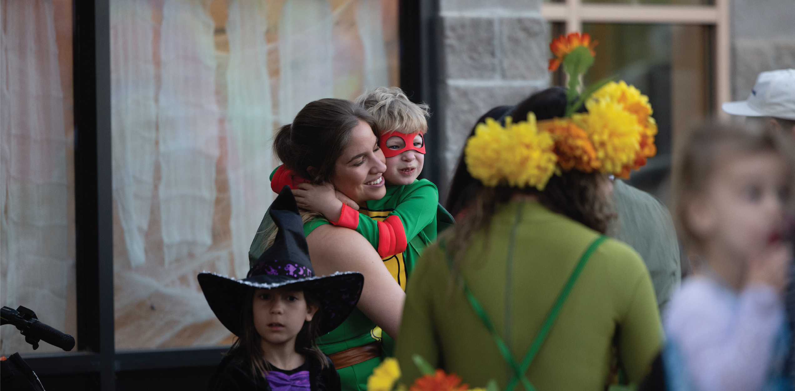 Parent and child dressed as Ninja Turtles hugging aggressively.