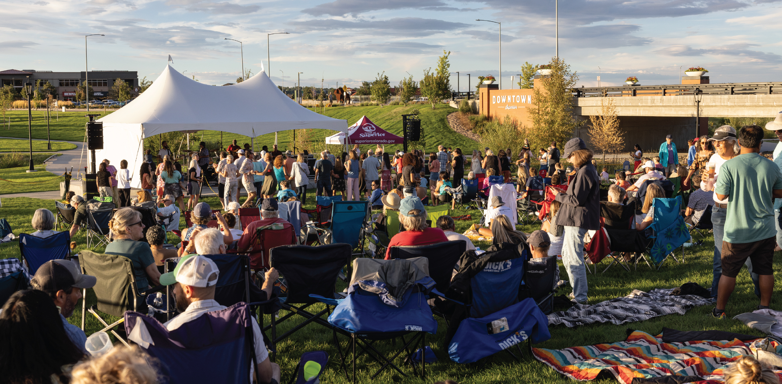 Wide shot of the event with the Downtown Superior sign lit up by the setting sun in the background.