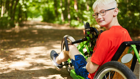 A young boy on a recumbent tricycle on a trail