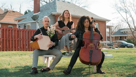 Deborah Solo Trio sitting on a bench with instruments