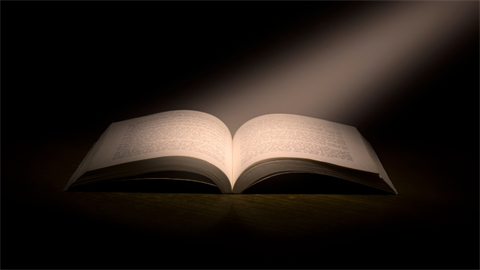 An open book illuminated by a spotlight