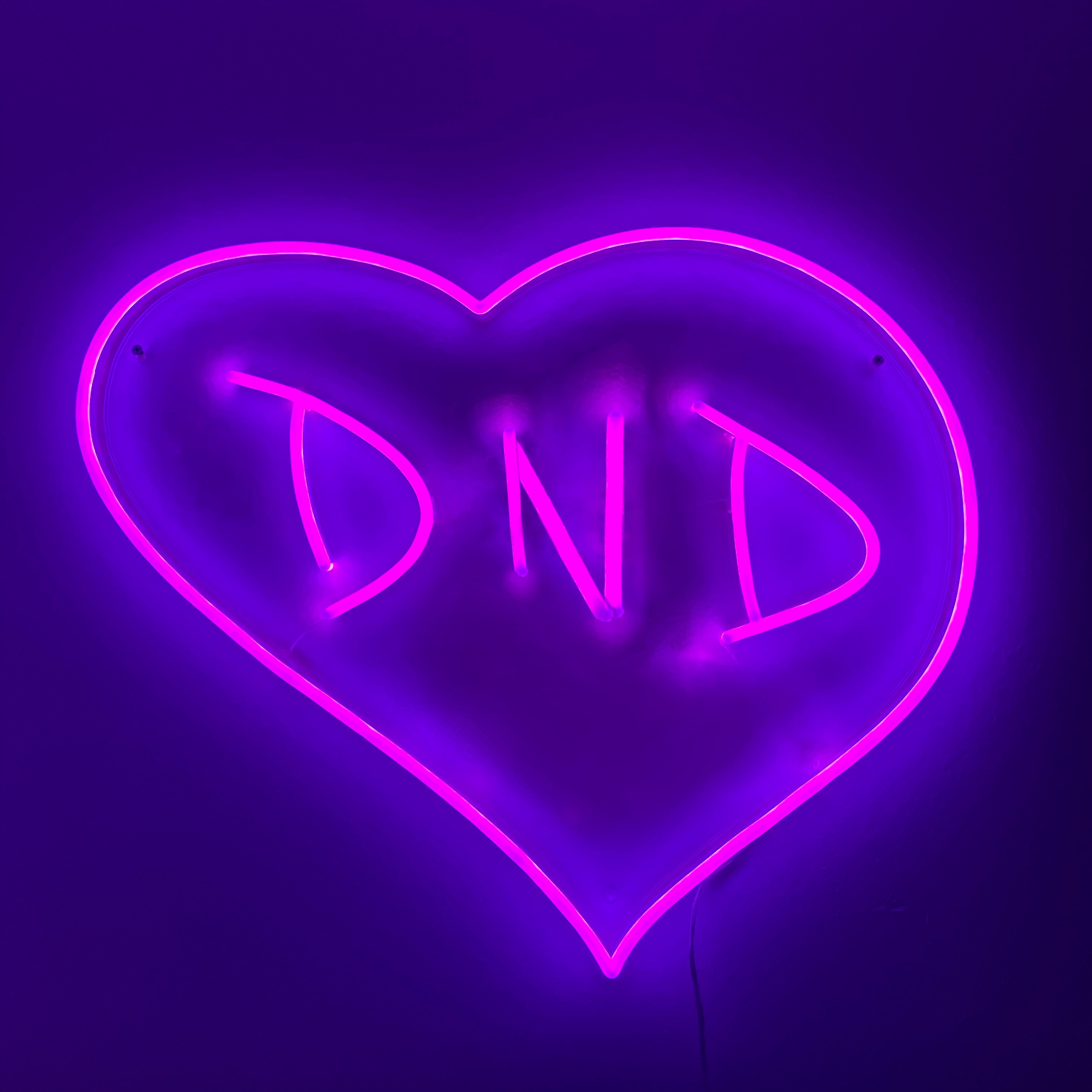 neon purple sign in the shape of a heart with the letters 