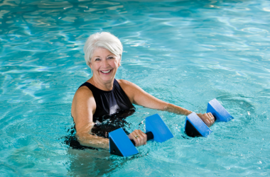 Water aerobics instructor with hand weights in a pool