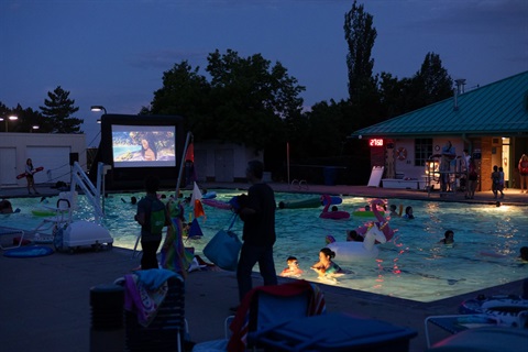 flick & float event at the north pool, moana is playing on the big screen TV & the pool is filled with people & floaties